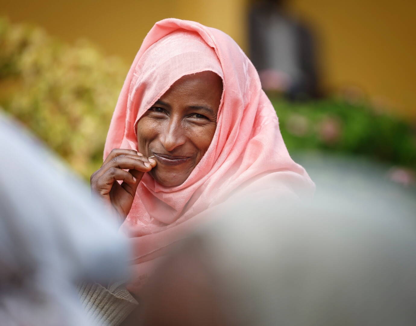 Jetzt spenden! Eine Frau lacht schüchtern in die Kamera.