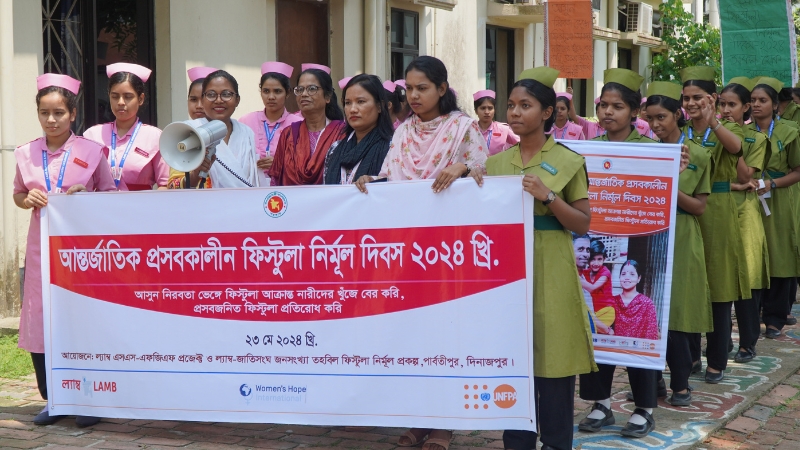 Starke Gesundheitsdienste, weniger Geburtsfisteln Frauen laufen in einer Reihe und halten ein Transparent hoch.