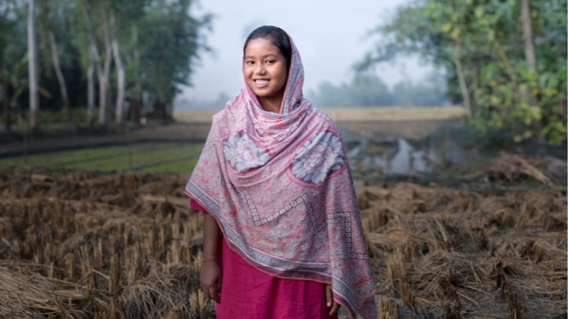 Ujalas Geschichte Eine junge Frau lacht stolz in die Kamera.