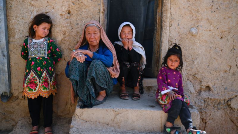 Fünf Jahre Taliban Eine alte Frau sitzt auf einer Treppe, umringt von drei Mädchen.
