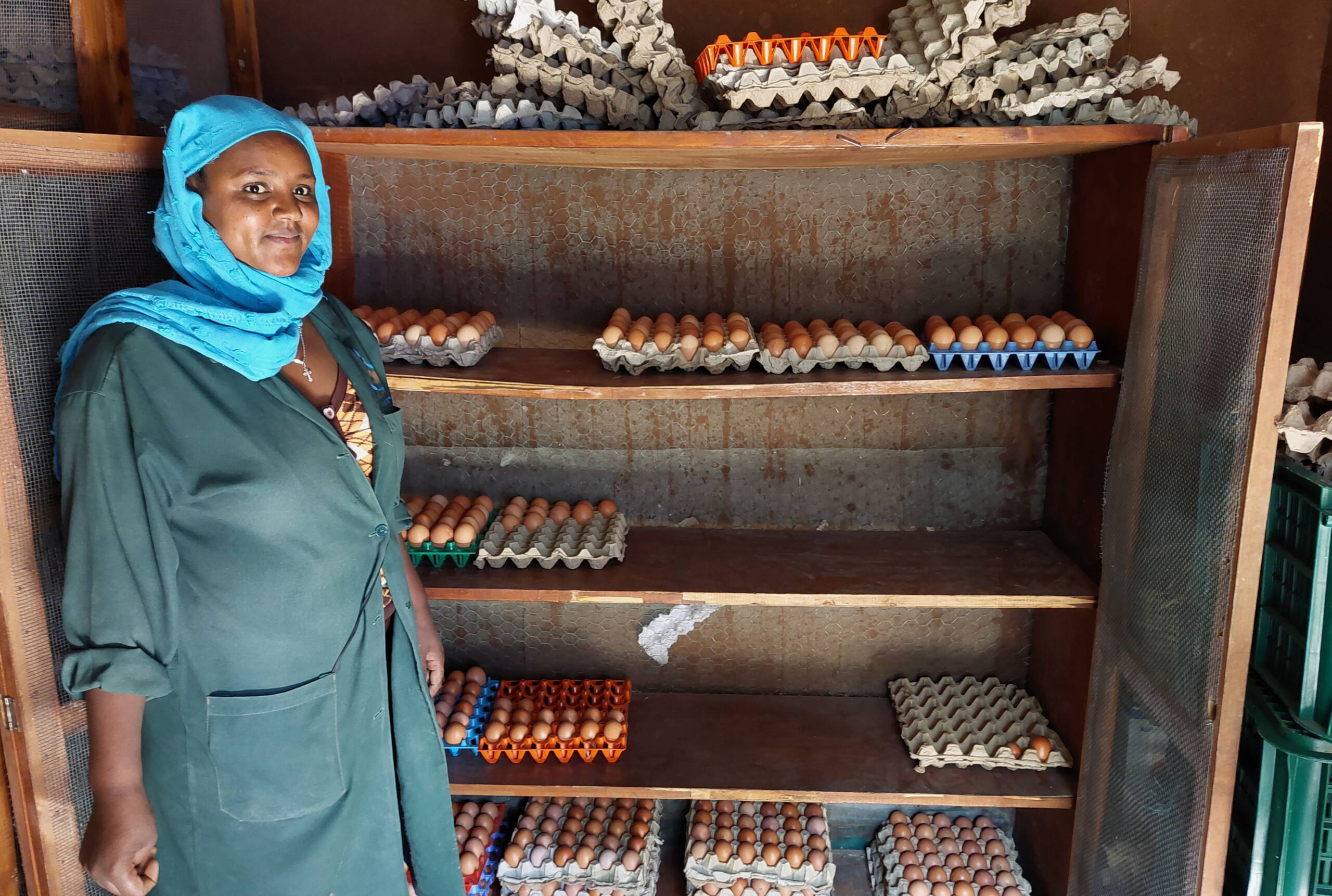Hühnerzucht Eine Frau steht stolz vor einem Gestell mit Hühnereier.