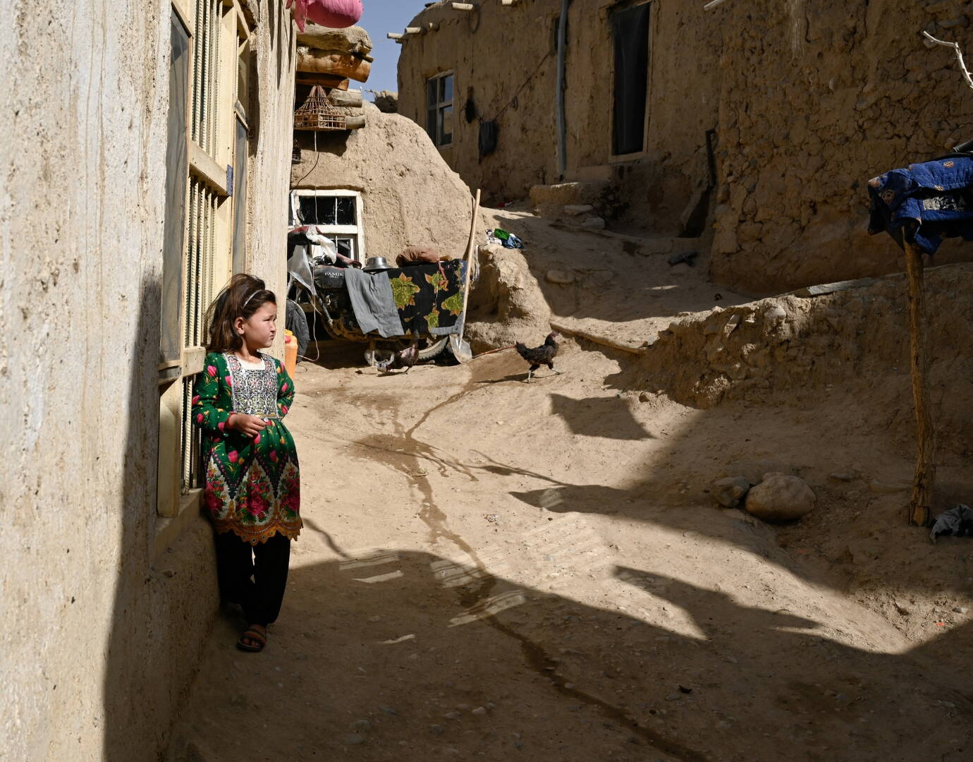 Jetzt spenden! Ein Mädchen steht an Hausmauer gelehnt und schaut unsicher um sich.