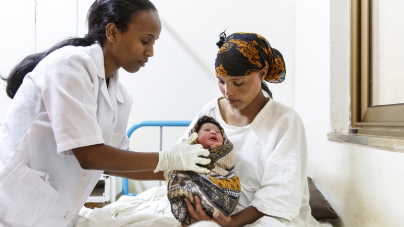 Women’s Hope International lanciert Appell für sichere Geburten Eine Hebamme hält einer Mutter ihr Neugeborenes hin.