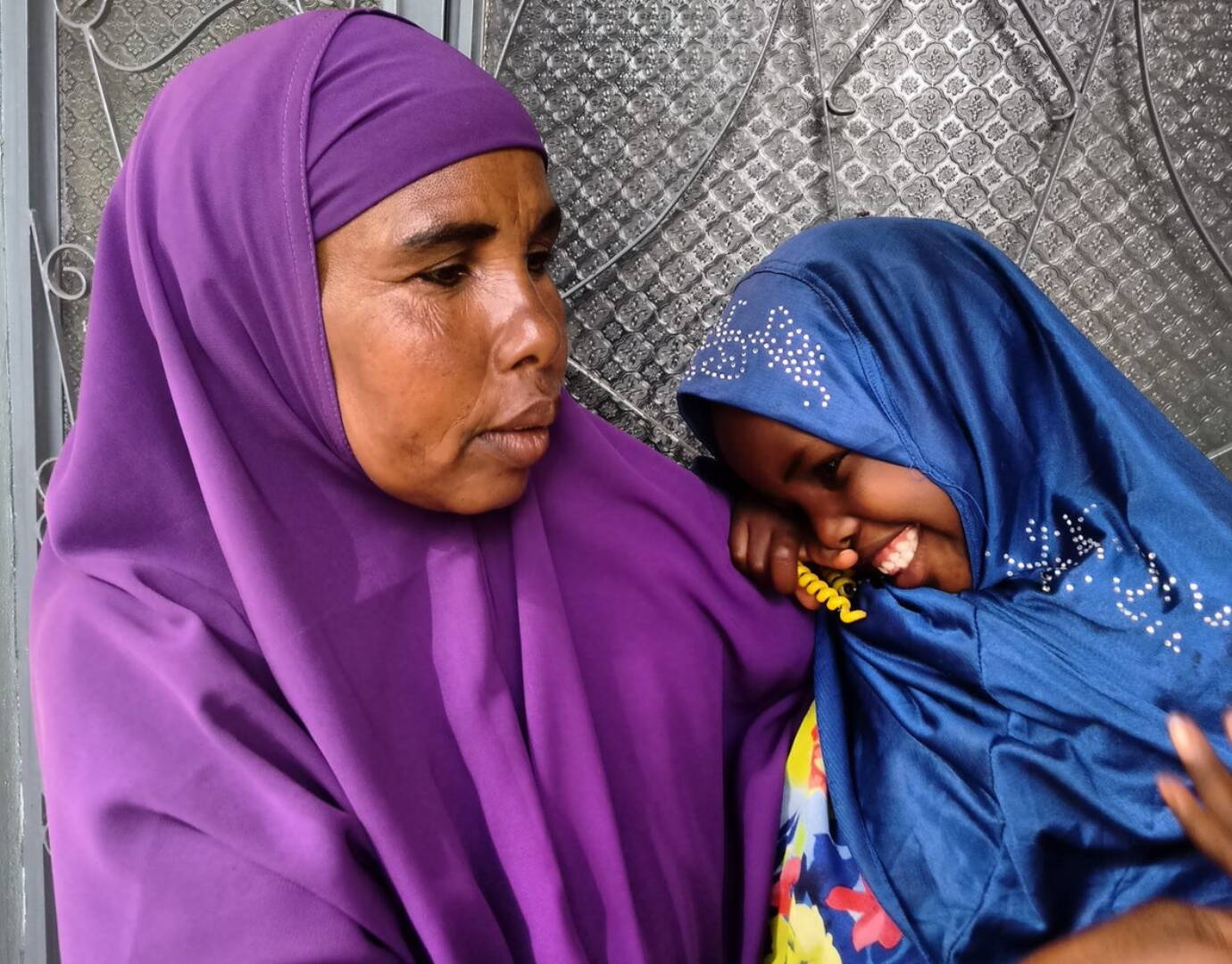 Jetzt spenden! Ein Mädchen kuschelt sich vertrauensvoll an eine ältere Frau.