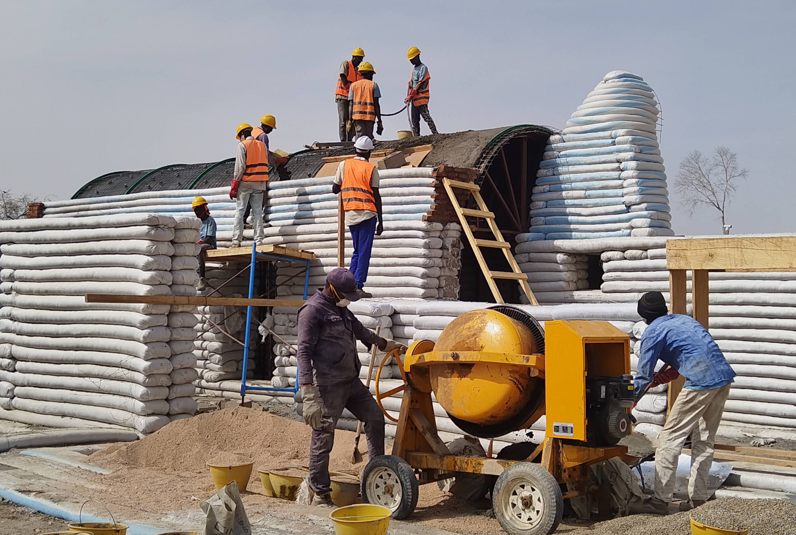 Bau Wartesaal Bauarbeiter arbeiten an einem Gebäude, das aus geschichteten Sandsäcken besteht.